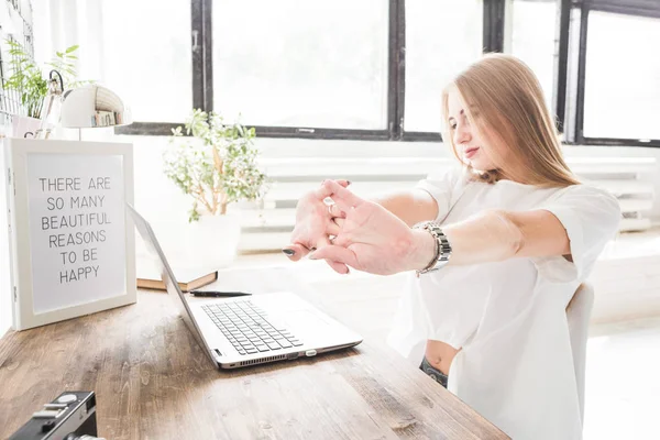 Jovem mulher de negócios trabalhando em casa atrás de um laptop e esticando as mãos. Espaço de trabalho estilo escandinavo criativo — Fotografia de Stock