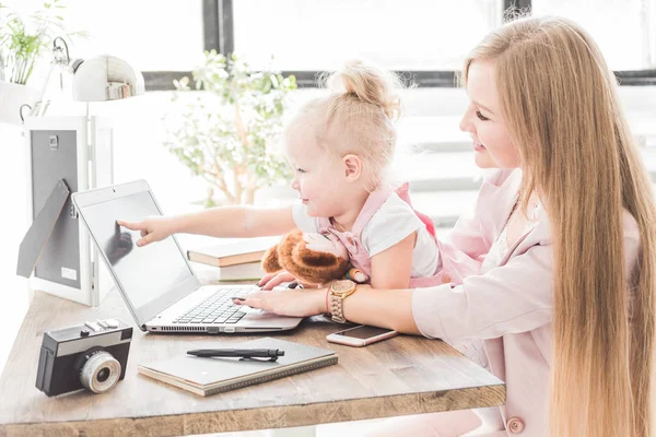 Joven mujer de negocios que trabaja en casa detrás del portátil con un niño pequeño. Espacio de trabajo de estilo escandinavo creativo. Trabajos sobre el permiso de maternidad — Foto de Stock