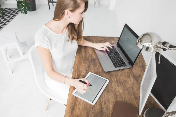 Joven mujer de negocios que trabaja en casa y se basa en la tableta. Espacio de trabajo de estilo escandinavo creativo — Foto de Stock