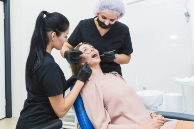 Diş Kliniği. Resepsiyon, hastanın incelenmesi. Diş Bakımı. Genç kadın bir diş muayenesi bir diş hekimi tarafından geçer