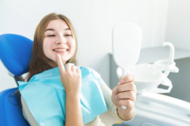 Diş Kliniği. Resepsiyon, hastanın incelenmesi. Diş Bakımı. Genç kız gülümseyerek, onun diş hekimi, diş muayenesi sonra aynaya bakıyorum