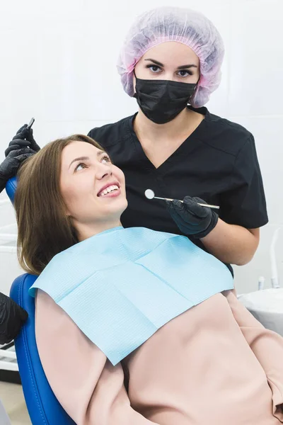 Clínica dental. Recepción, examen del paciente. Cuidado de los dientes. Mujer joven se somete a un examen dental por un dentista — Foto de Stock