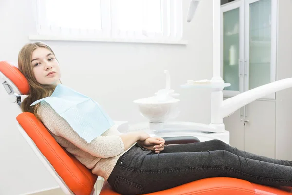Clínica dentária. Recepção, exame do paciente. Cuidado com os dentes. A menina está sentada na cadeira dentária pronta para examinar os dentes — Fotografia de Stock