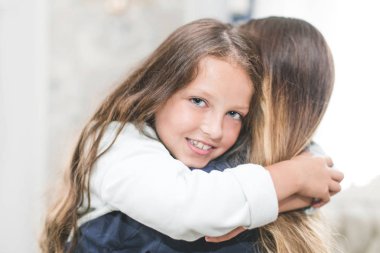 Güzel genç kadın ve sevimli küçük kızını sarılma ve gülümseyen