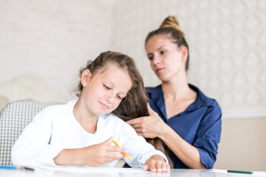 Mutlu sevgi dolu aile. Anne ve kızı saç yapıyorsun. rüya gibi çocuk kız çizim ve boya ile renkli kalemler
