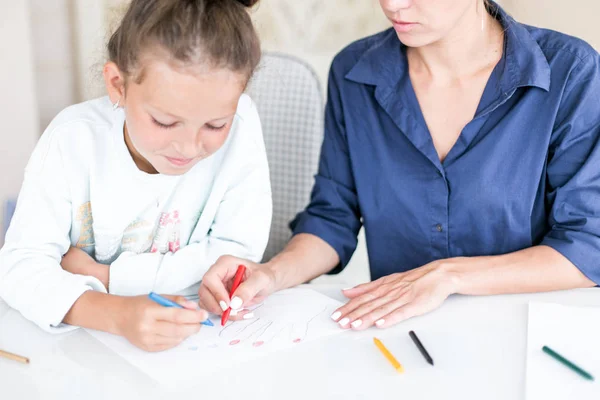 Familia feliz. Madre e hija juntas pintan y dibujan. Mujer adulta ayuda a la niña — Foto de Stock