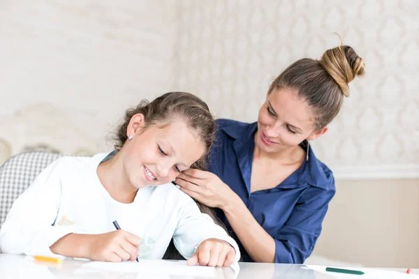 Feliz familia amorosa. Madre e hija están peinando. niña soñadora dibujo y pintura con lápices de color — Foto de Stock