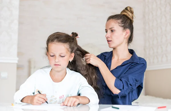 Feliz familia amorosa. Madre e hija están peinando. niña soñadora dibujo y pintura con lápices de color — Foto de Stock