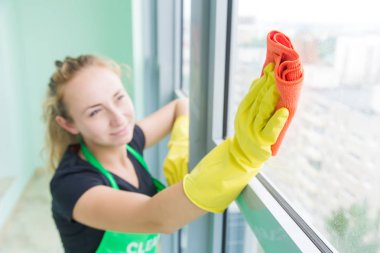 Camsil ve bez ile sabun köpük cam pencere üzerinde temizlik işçisi genç kadın gülümseyerek