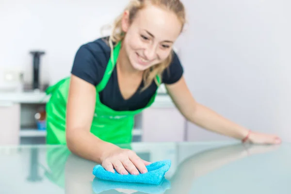 Temizlik hizmeti. Genç bir kadın apronda bir bez ile Toz bezleri — Stok fotoğraf