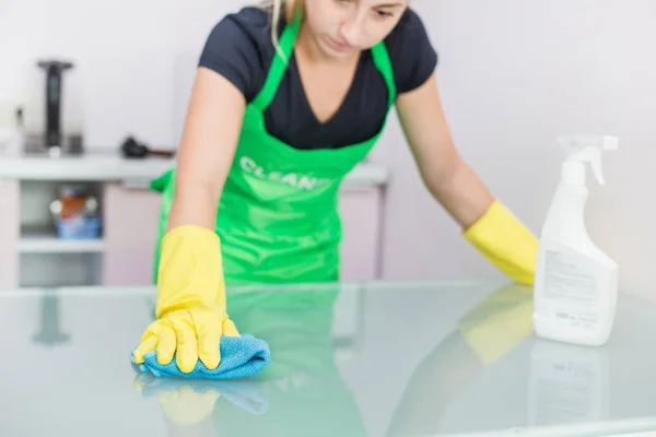 Usługa sprzątania. Młoda kobieta w fartuch wycierać kurz szmatką — Zdjęcie stockowe