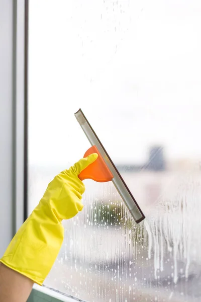 Worker cleaning soap suds on glass window with squeegee and rag — Stock Photo, Image