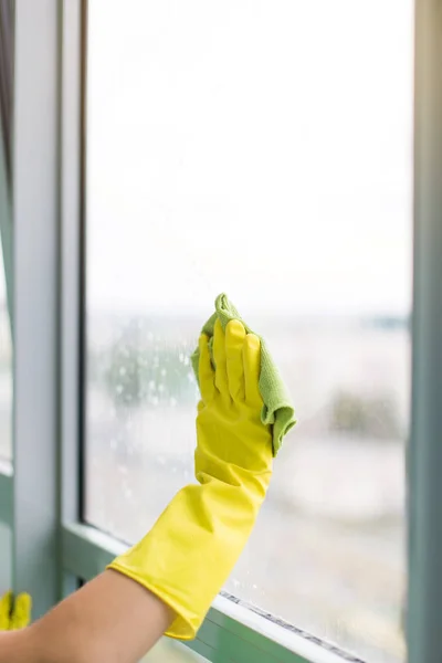 Sonriente joven trabajadora de limpieza jabón suds en ventana de vidrio con escobilla y trapo —  Fotos de Stock