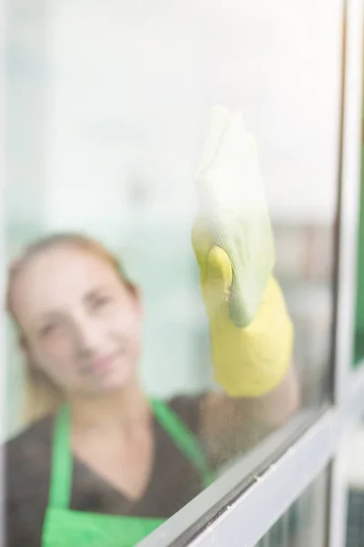 Smiling young woman worker cleaning soap suds on glass window with squeegee and rag — Stock Photo, Image