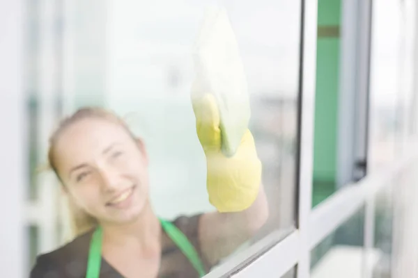 Sorrindo jovem trabalhador limpeza sabão suds na janela de vidro com rodo e pano — Fotografia de Stock