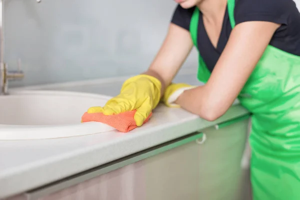 Primer plano de las manos femeninas en guantes de goma amarilla limpiando el panel de cocina en la cocina casera. Hogar, concepto de limpieza. servicio de limpieza — Foto de Stock