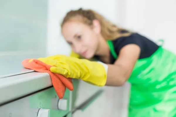 Primer plano de las manos femeninas en guantes de goma amarilla limpiando el panel de cocina en la cocina casera. Hogar, concepto de limpieza. servicio de limpieza —  Fotos de Stock