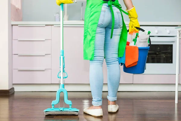 Paspas ve plastik kova fırçalar, eldiven ve deterjanlar ile mutfakta tutan kadın — Stok fotoğraf