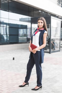 Güzel kadın ofis binası yürüyüş kahve ile çalışma olacak. İş için yolda elinde sıcak bir içecek fincan şehir sokak üzerinde tutan başarılı iş kadın portresi.