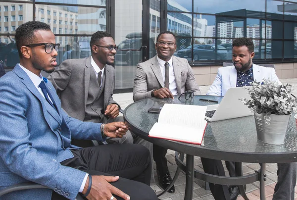 Group of happy diverse male and female business people team in formal gathered around laptop computer in bright office against the background of a glass building — Stock Photo, Image
