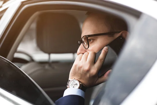 Młodym biznesmenem rozmawia przez telefon, siedzący na tylnym siedzeniu elity samochodów, rozmów i spotkań biznesowych — Zdjęcie stockowe