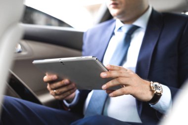 Genç işadamı bir arabanın arka koltuğunda otururken Tablet PC'yi kullanma. Beyaz erkek iş bir taksi ile yönetici ve dijital tablet bakarak.