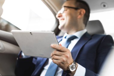 Genç işadamı bir arabanın arka koltuğunda otururken Tablet PC'yi kullanma. Beyaz erkek iş bir taksi ile yönetici ve dijital tablet bakarak.