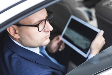 Genç işadamı bir arabanın arka koltuğunda otururken Tablet PC'yi kullanma. Beyaz erkek iş bir taksi ile yönetici ve dijital tablet bakarak.
