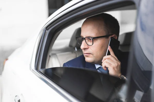 Młodym biznesmenem rozmawia przez telefon, siedzący na tylnym siedzeniu elity samochodów, rozmów i spotkań biznesowych — Zdjęcie stockowe