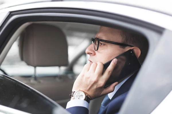 Fiatal sikeres üzletember, beszél a telefonon, ült a hátsó ülésen egy elit autó, tárgyalások és üzleti találkozók — Stock Fotó