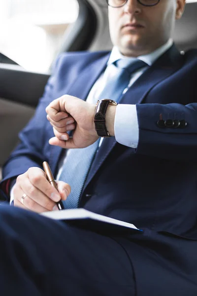 El hombre en el traje de trabajo escriben en el portátil con el portátil en el salón del automóvil caro con el interior de cuero — Foto de Stock