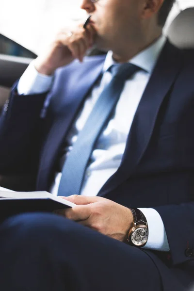 El hombre en el traje de trabajo escriben en el portátil con el portátil en el salón del automóvil caro con el interior de cuero — Foto de Stock