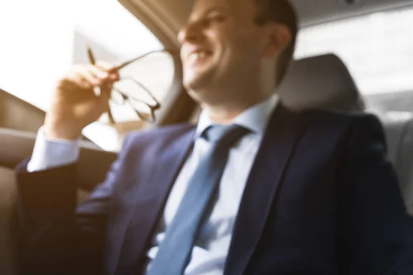 Man in a business suit write on notebook with laptop in the salon of an expensive car with leather interior