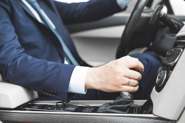 Бизнесмен за рулем машины. Ручной макро на коробке передач, переключение передач
