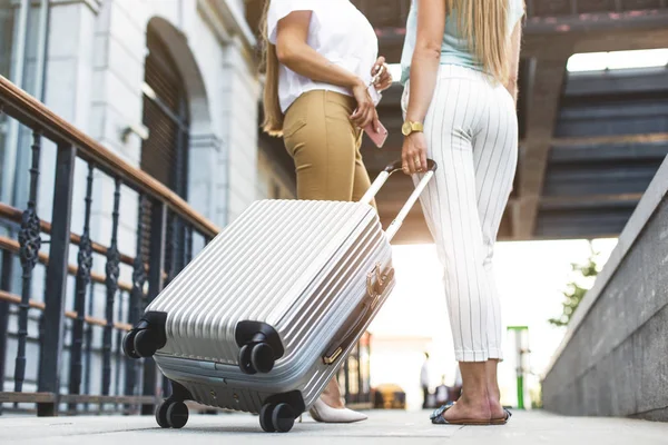 Dos hermosas rubias chicas jóvenes con maletas en el fondo de un hotel caro. Amigos de un turista de vacaciones con equipaje — Foto de Stock