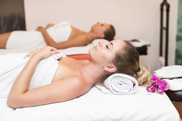 Две милые молодые женщины наслаждаются во время процедуры по уходу за кожей в спа. массаж и косметические процедуры в салоне красоты — стоковое фото