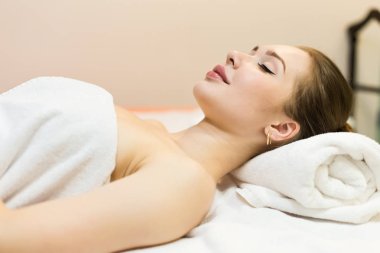 Genç güzel kız spa salonda. Kız bir gençleştirme işlemden sonra bir masaj için kanepede yatıyor