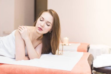 Genç güzel kız spa salonda. Kız bir gençleştirme işlemden sonra bir masaj için kanepede yatıyor