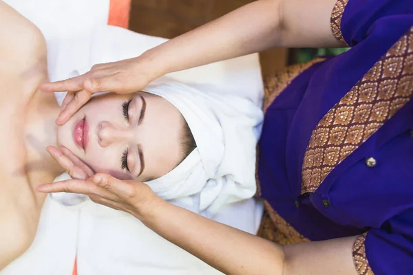 beautiful girl enjoys face massage in spa salon. Procedures for beauty and rejuvenation. Thai massage