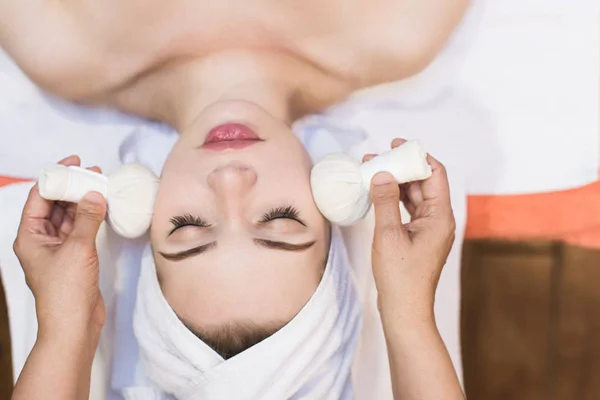 beautiful girl enjoys face massage in spa salon. Procedures for beauty and rejuvenation. Thai massage