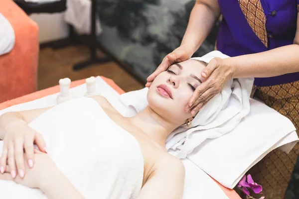 beautiful girl enjoys face massage in spa salon. Procedures for beauty and rejuvenation. Thai massage