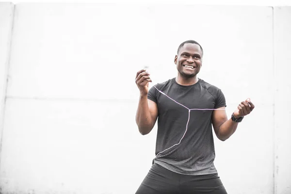 Smiling Young male jogger athlete training and doing workout outdoors in city. a black man resting after a workout and listening to music and watching a sports watch. free copyspace for text