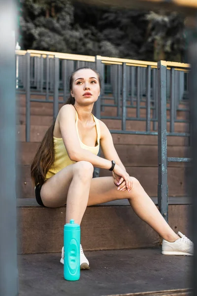 Una joven corredora calentándose antes de correr por la ciudad. una chica descanso después de practicar deportes —  Fotos de Stock