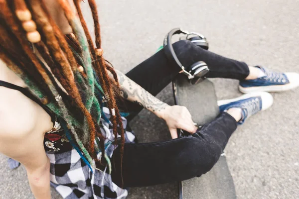 Chica joven con tatuaje y rastas sentado en el parque —  Fotos de Stock