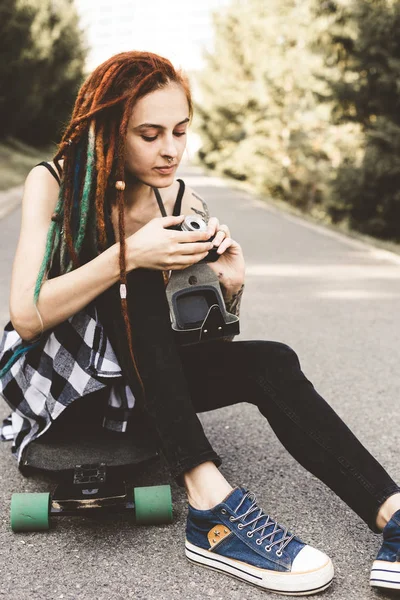 Молода дівчина з татуюваннями та дредлоками фотографії старовинної камери в парку — стокове фото