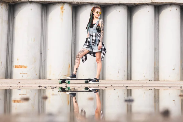 콘크리트 구조물의 배경에 longboard와 어린 소녀 — 스톡 사진