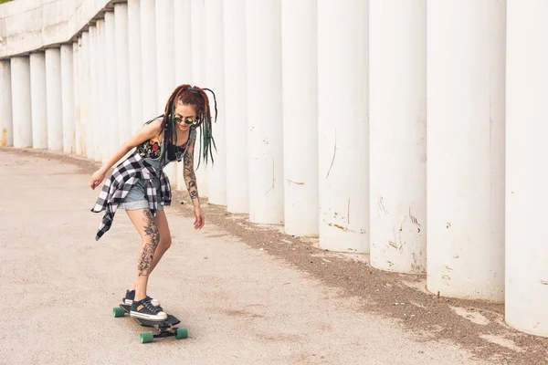 Chica joven con tatuajes paseos en un longboard —  Fotos de Stock