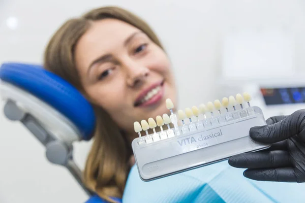 Clínica dentária. Recepção, exame do paciente. Cuidado com os dentes. Dentista com amostras de cor de dente escolhendo sombra para mulheres dentes de paciente na clínica odontológica — Fotografia de Stock