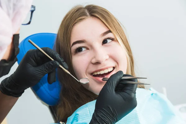 Clínica dental. Recepción, examen del paciente. Cuidado de los dientes. Chica joven se somete a un examen dental por un dentista — Foto de Stock