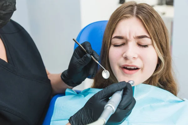 Clínica dental. Recepción, examen del paciente. Cuidado de los dientes. Chica joven siente dolor en el dentista — Foto de Stock